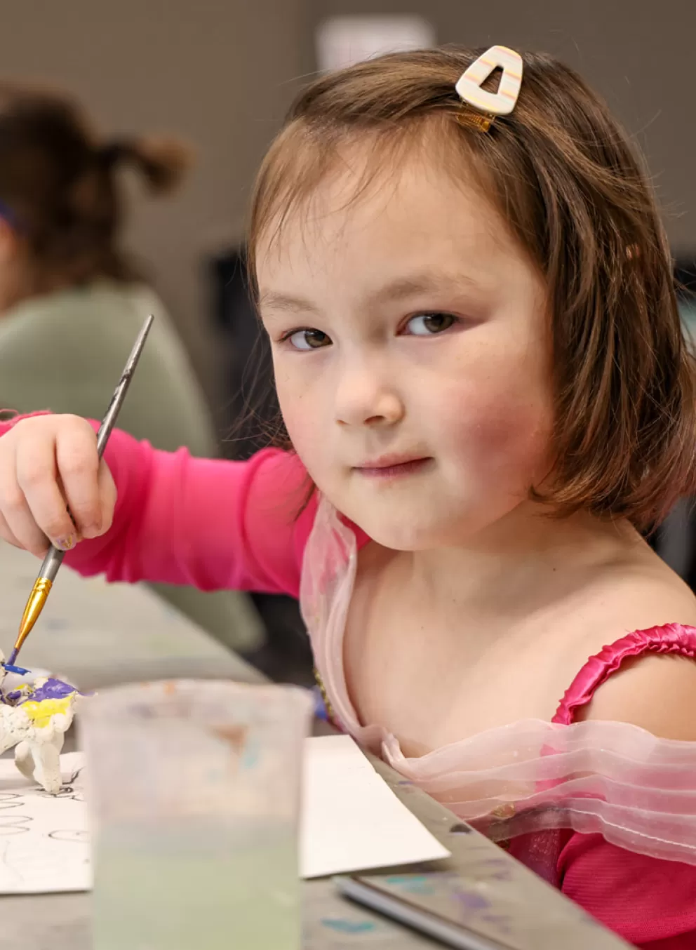 A child poses for a photo while painting