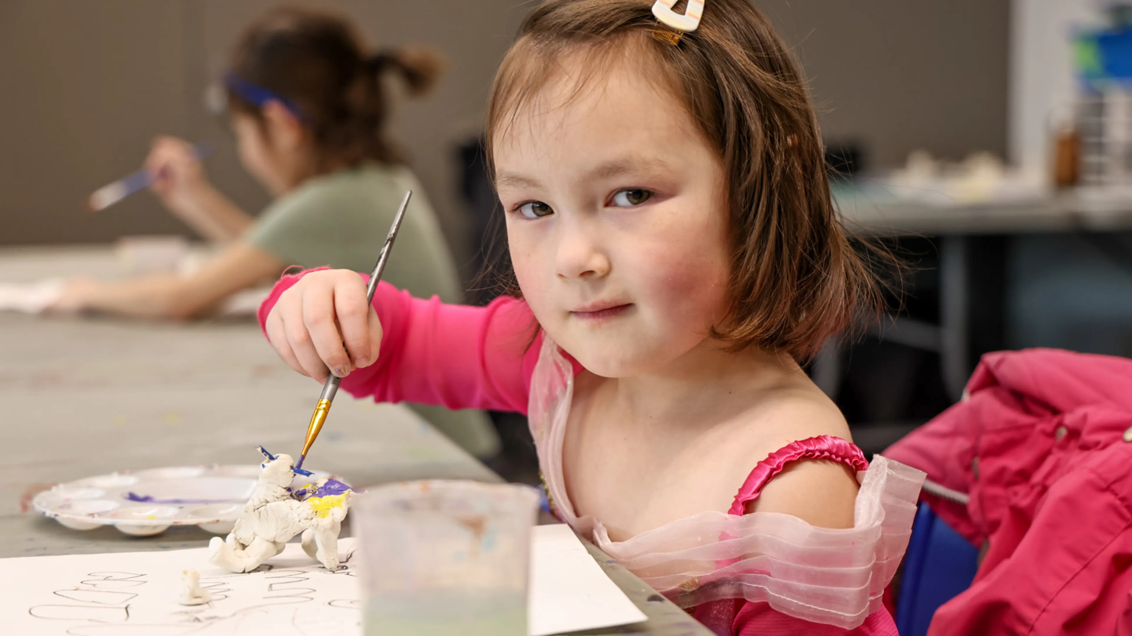 A child poses for a photo while painting