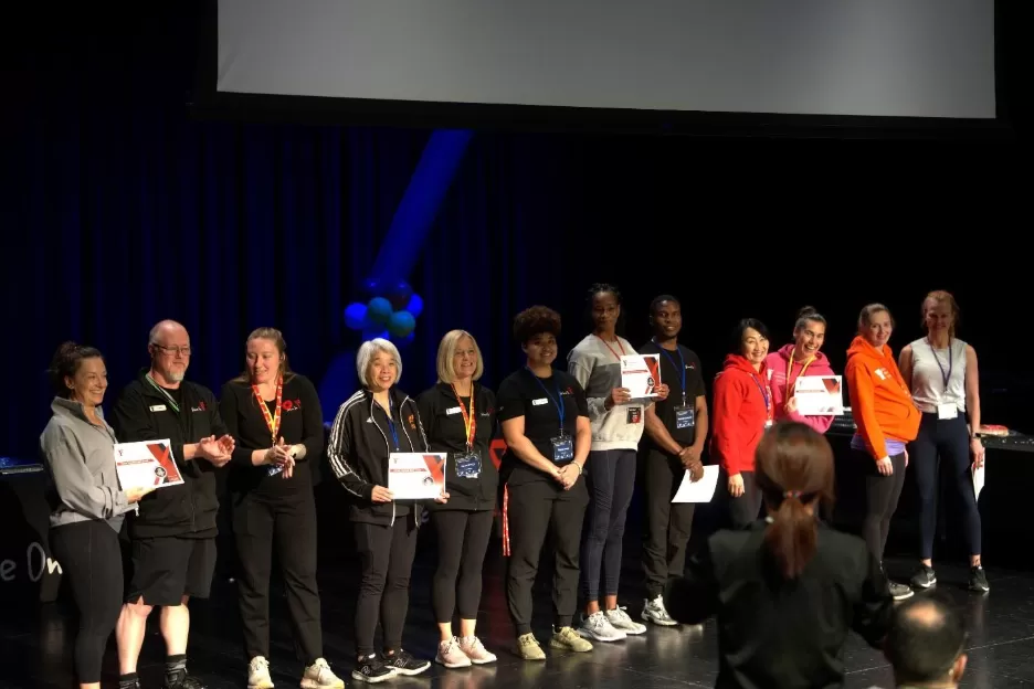 Group of people standing on stage with awards