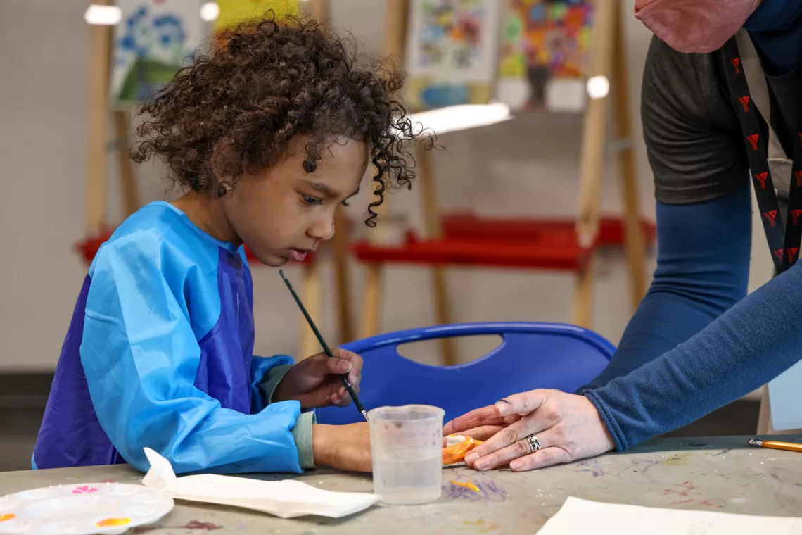 A young child paints in an art class