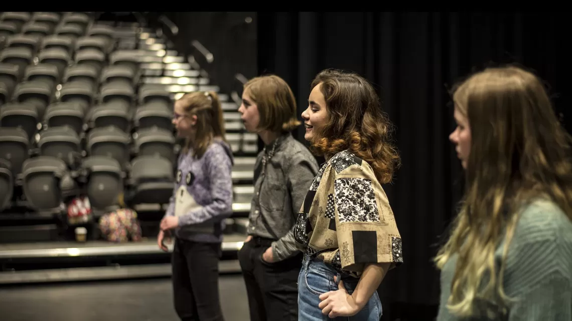 A group of youth stand together in a theatre